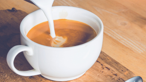 Creamer being poured into coffee mug